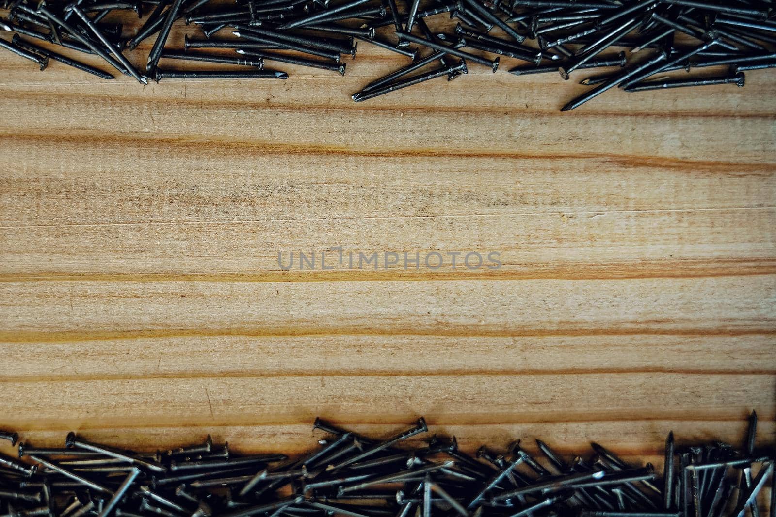 Small nails are scattered on the wooden Board. Background with space to copy. Advertising nails on wood