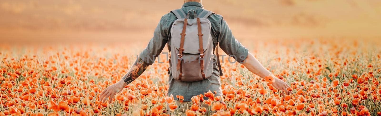 Backpacker man walking in poppies flower meadow. by alexAleksei