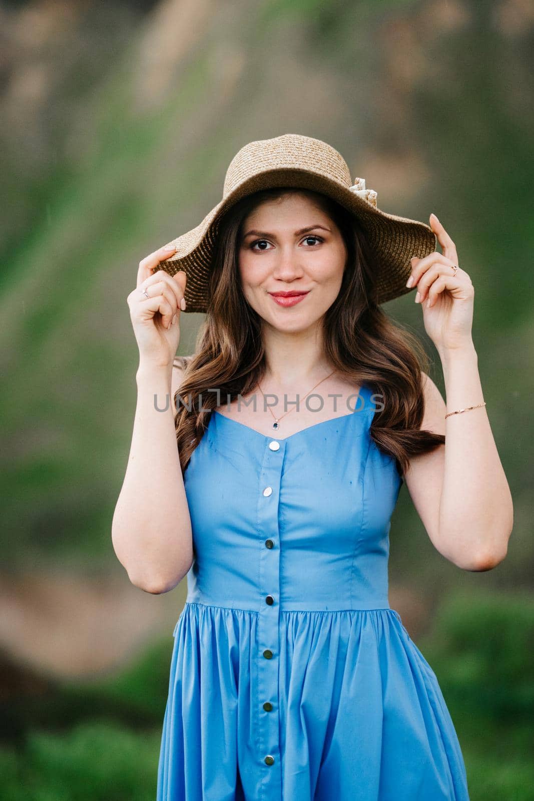 young girl in a straw hat with large brim on mountain green slopes