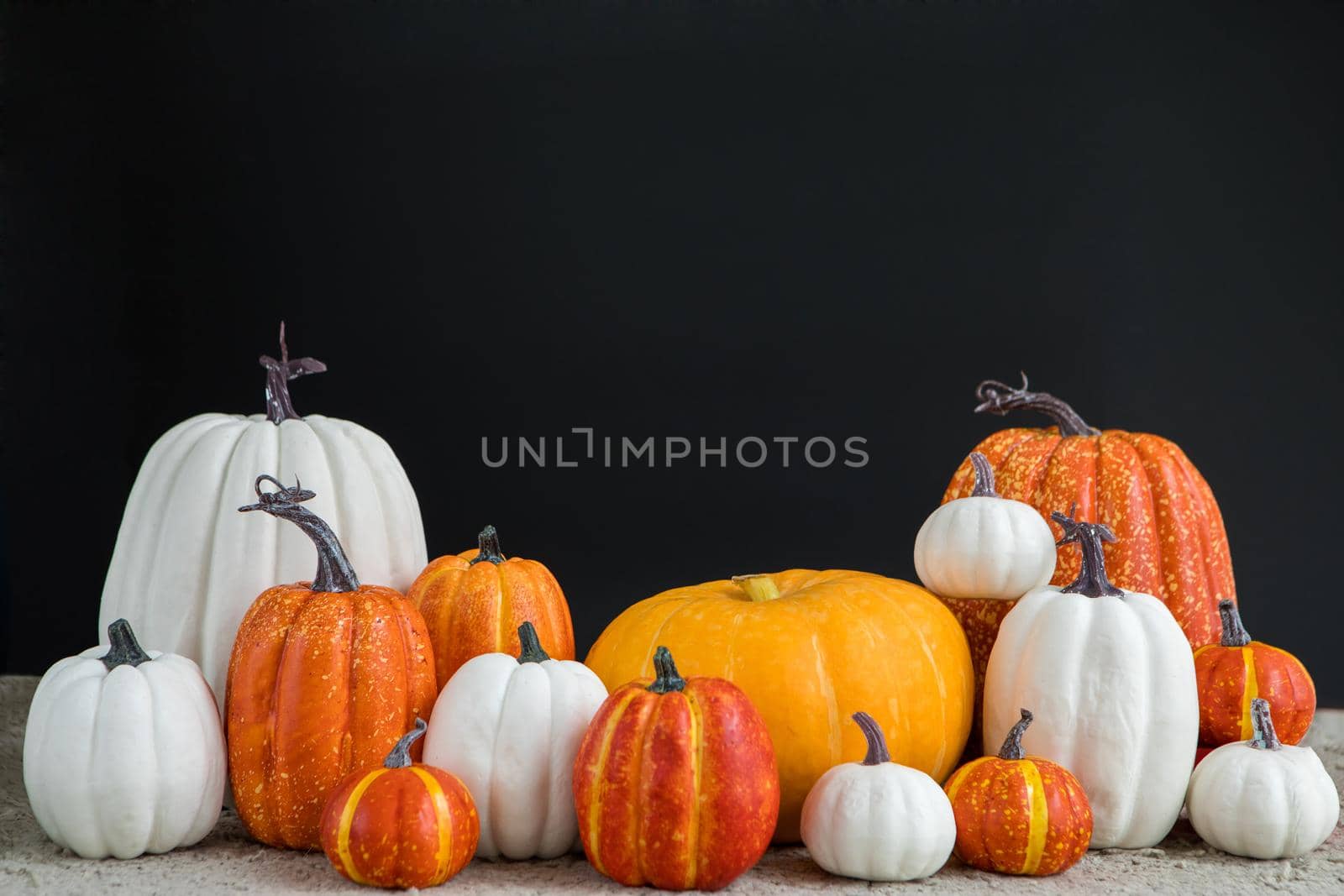 Bunch of various pumpkins on table black background by Demkat