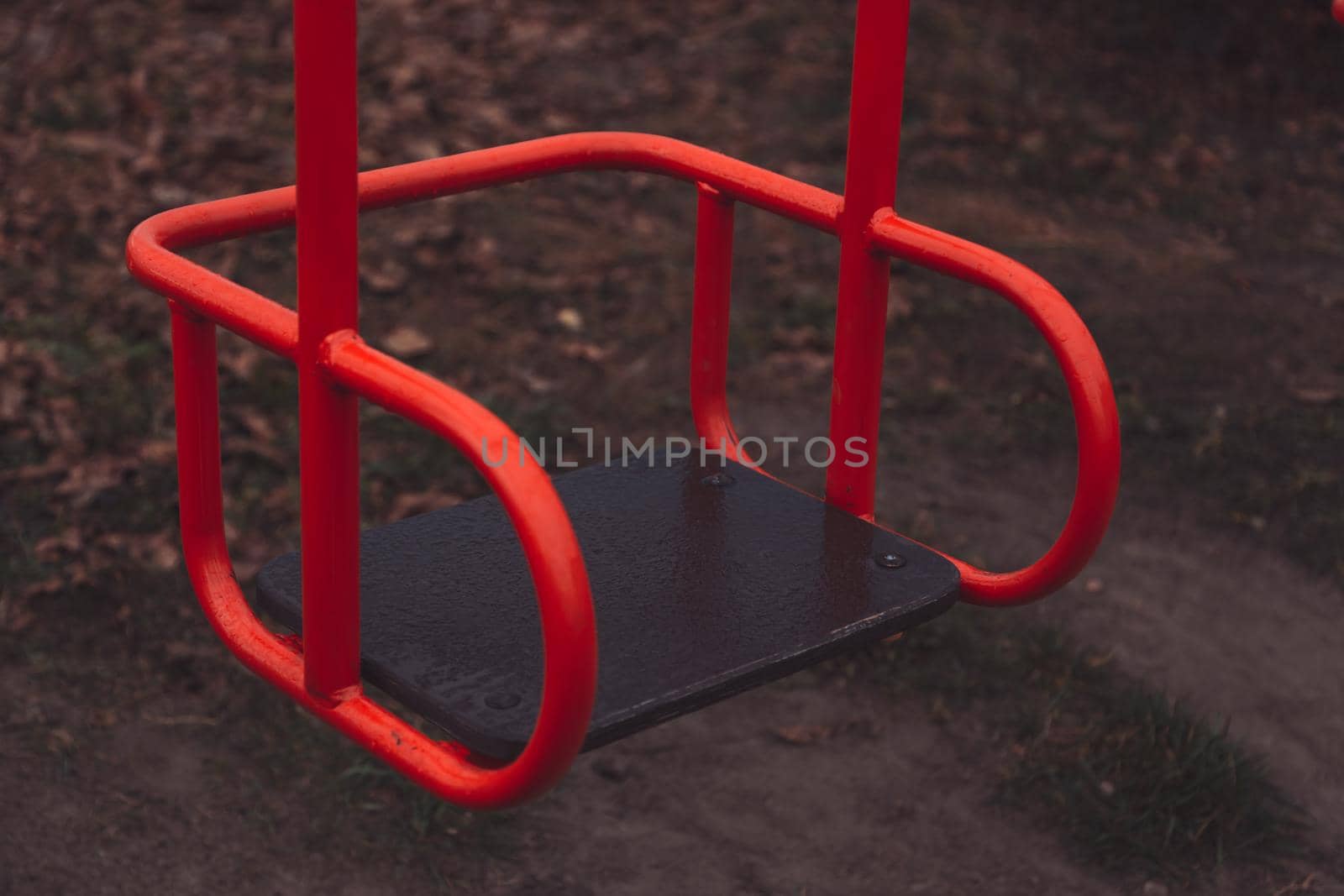 Empty children's swing red color close-up. The concept of sadness, loss, death, mourning, orphanhood or loneliness