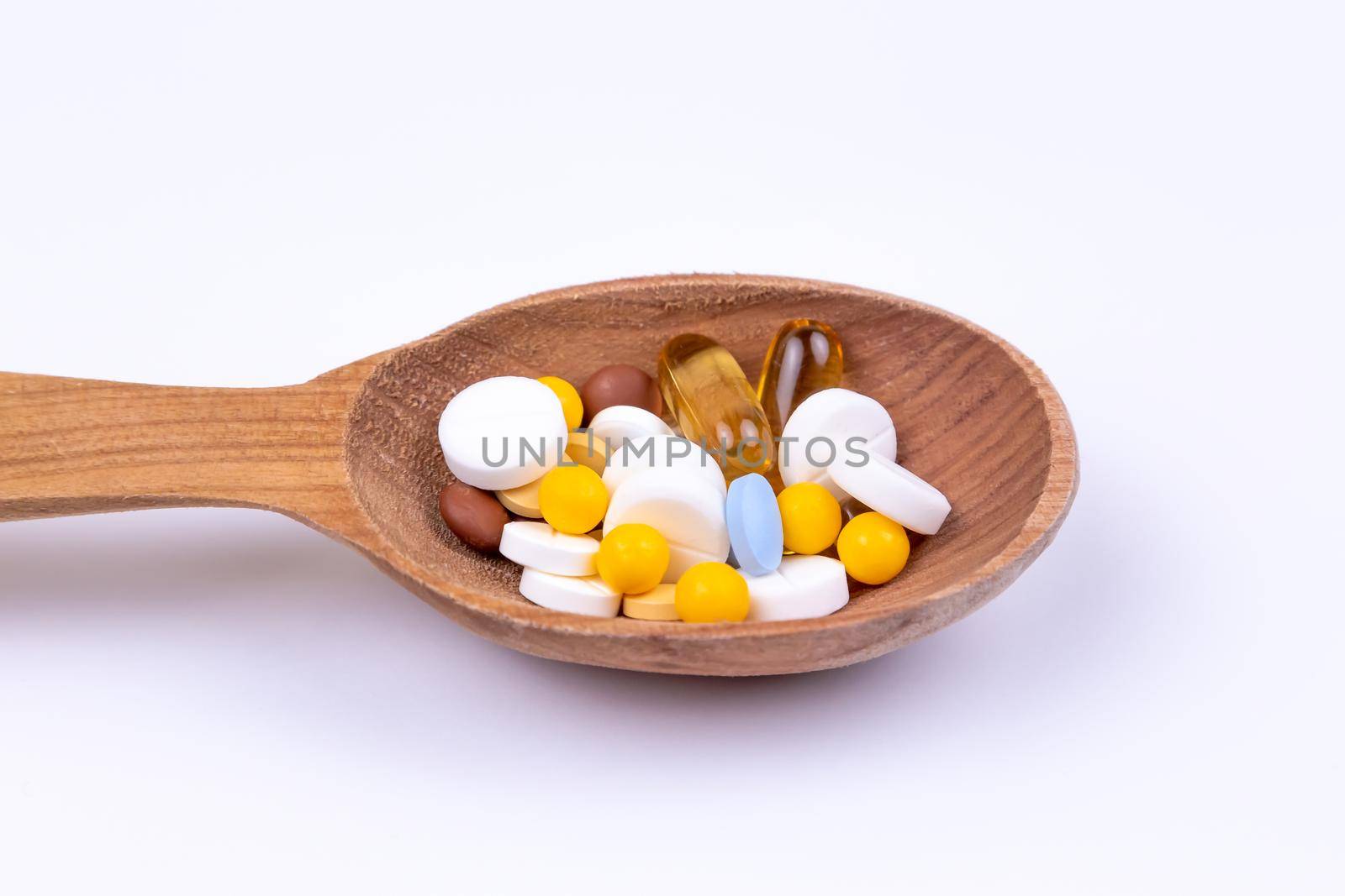 Medicine, pills and drug in wood spoon on white background with copy space.