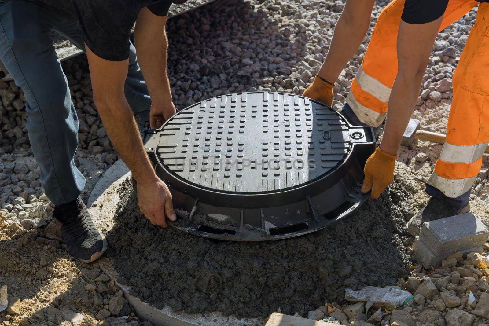 A worker installs a sewer manhole on a septic tank made of concrete rings by ungvar