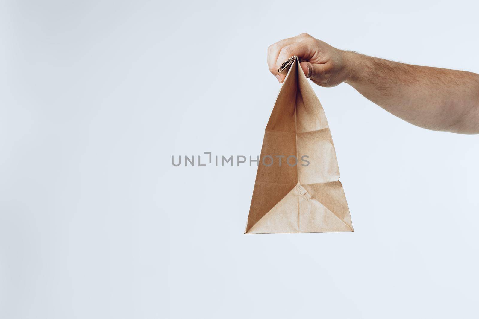 Courier hands giving packed food delivery close up against grey background