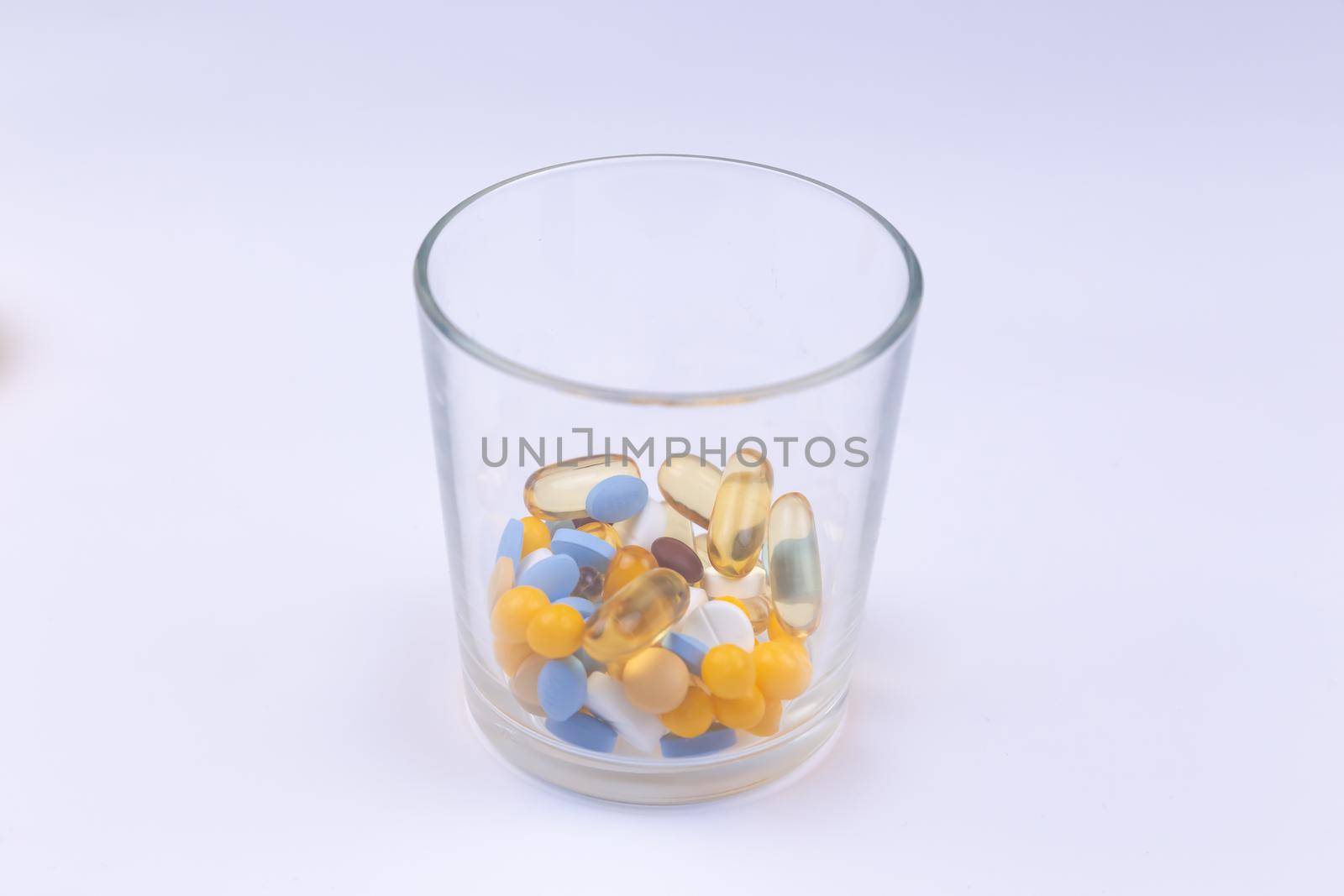 Dose of the colored pills in the glass of the package of pills. On white background with copy space for text.