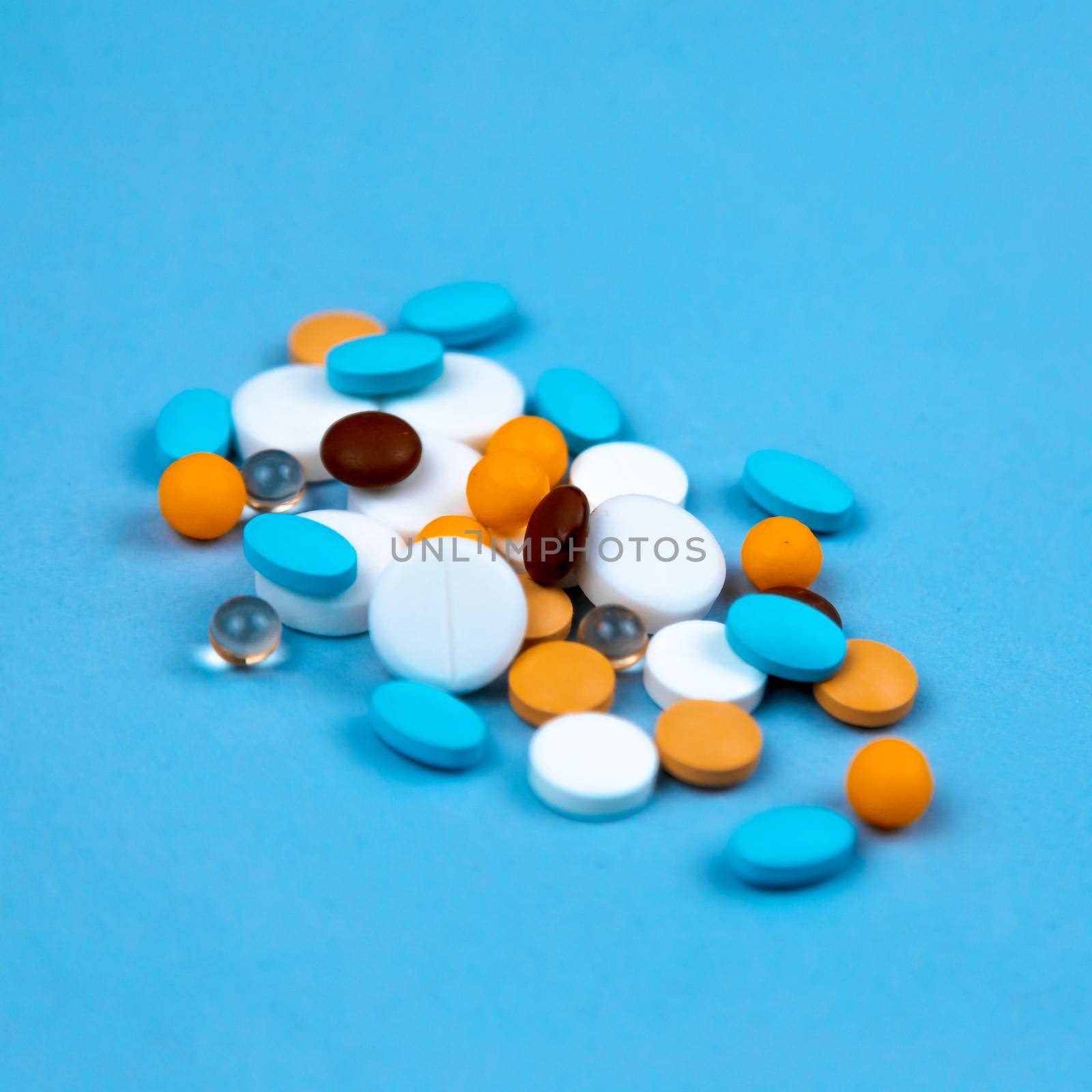 Multi-colored pills on a blue background close-up, with copy space for text.