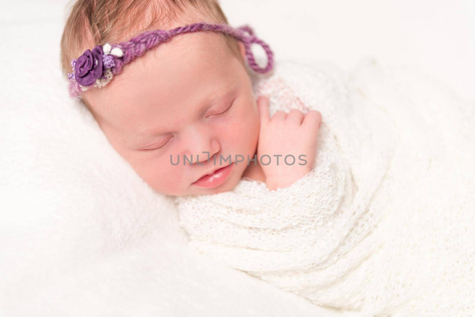 cute newborn baby in headband with flowers smiling asleep, closeup