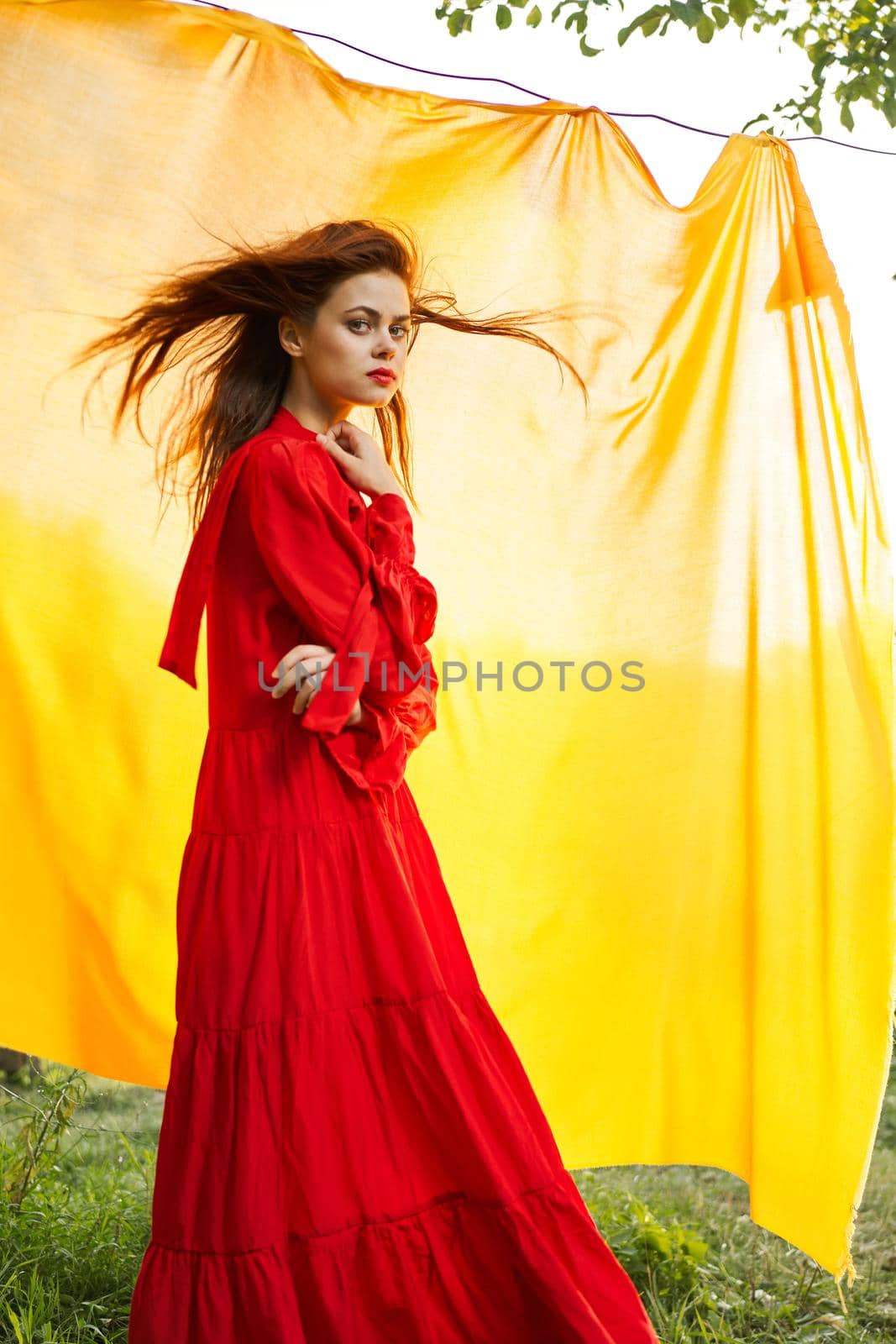 pretty woman in red dress yellow fabric on nature background. High quality photo