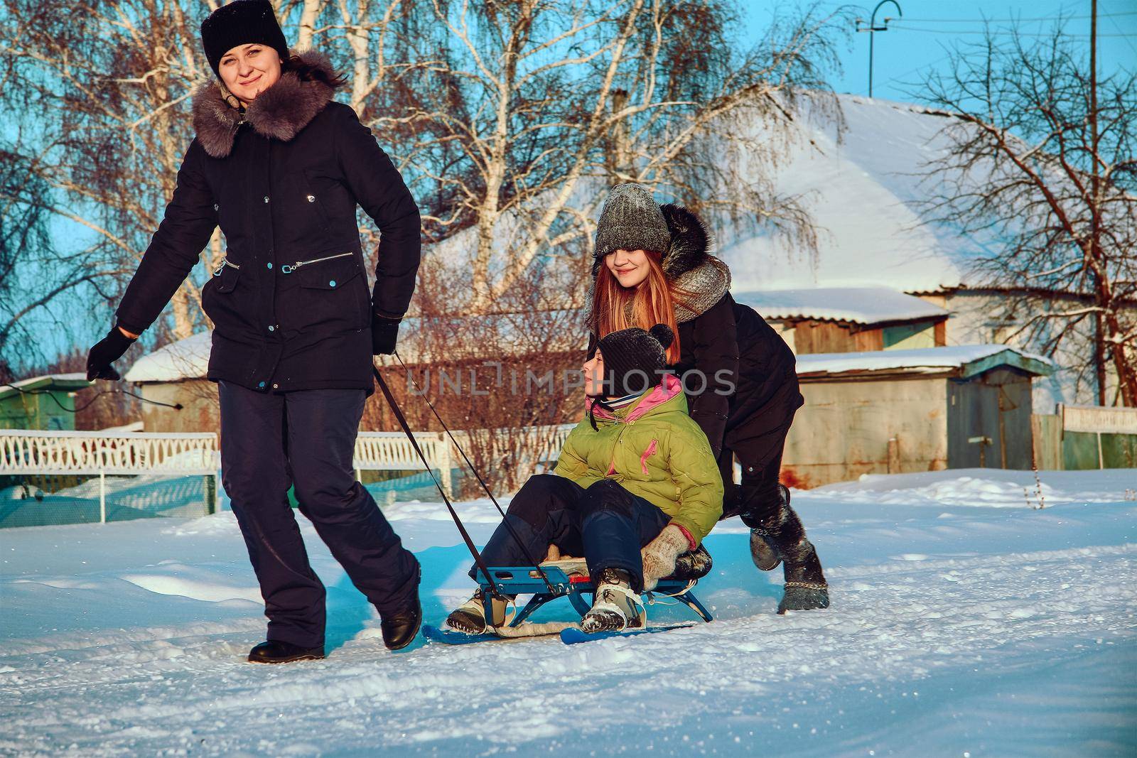 Village amusements in winter. Sledding in the rural hinterland. The family is relaxing in the open air.