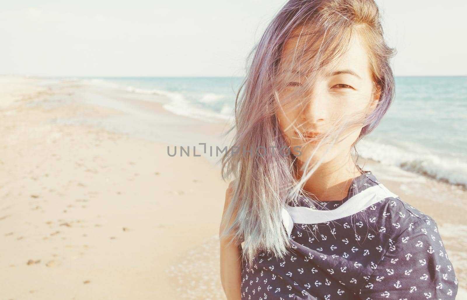 Portrait of mixed race young woman on background of sand beach and sea, looking at camera.