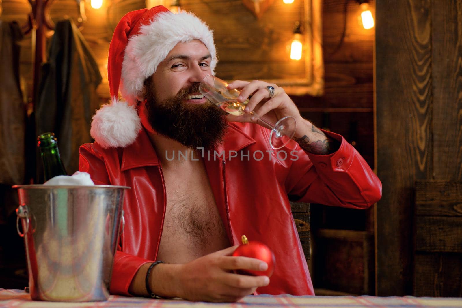 Bearded handsome man, Santa Claus with beard smile and drink champagne. Christmas lights garland. Merry christmas and happy new year. by Tverdokhlib