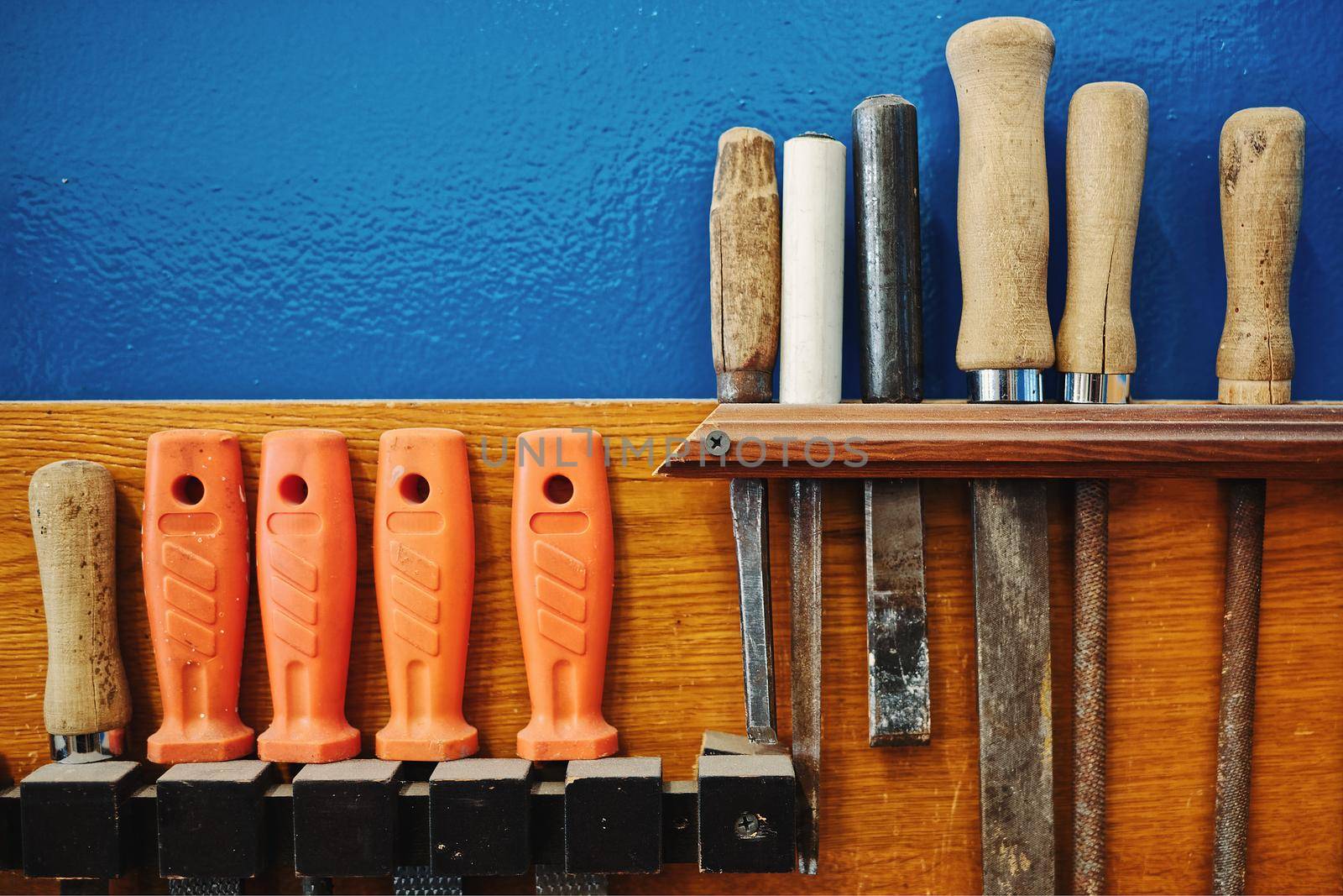 The carpenter's tools hang neatly on the wall. Workplace order. Rashpil, file and chisel close-up. Copy space.