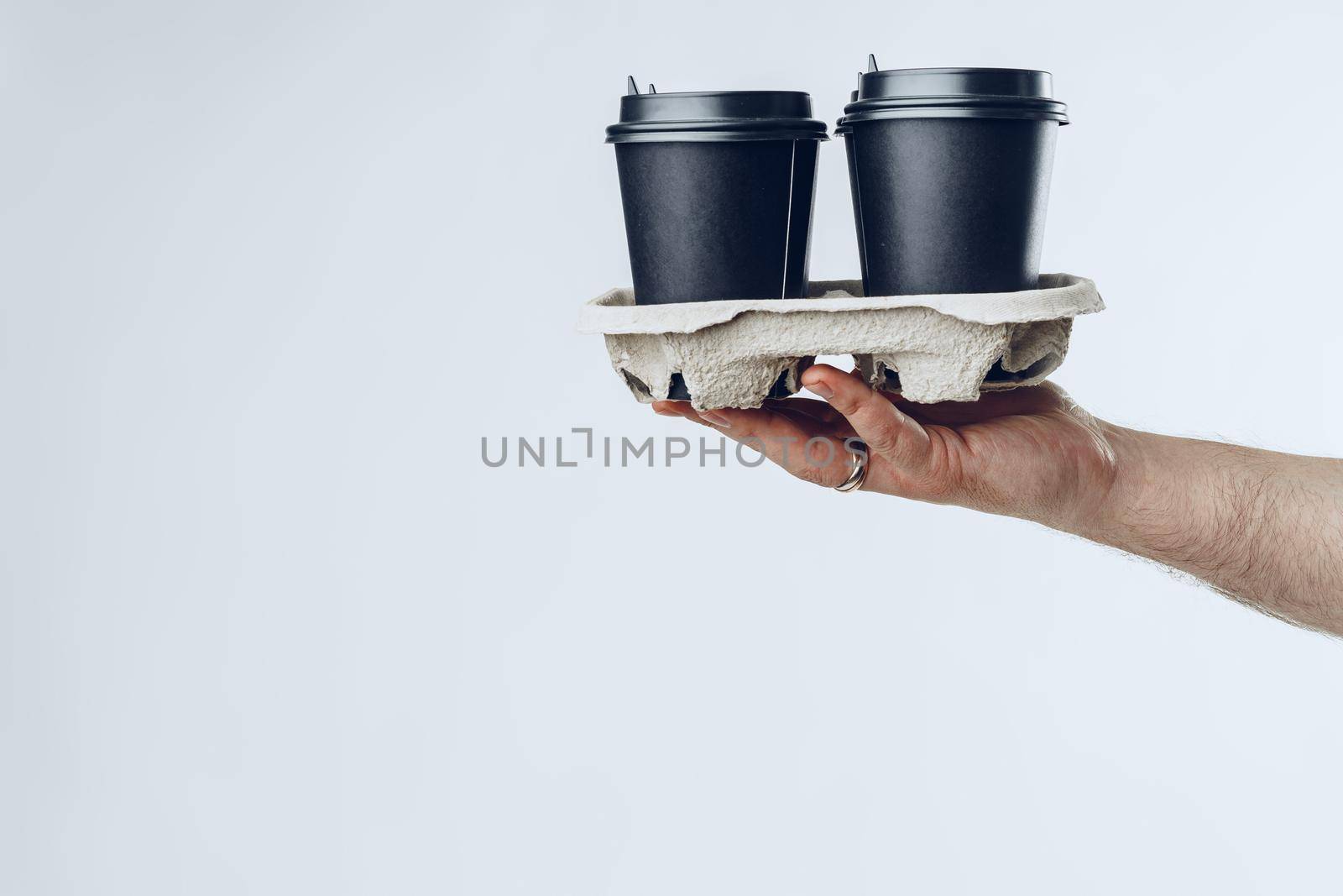 Courier hands giving packed food delivery close up against grey background