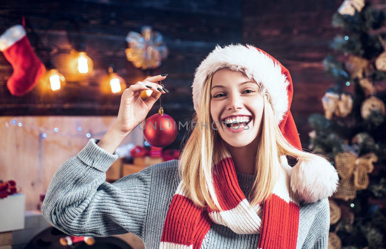 Happy girl decorate the Christmas tree indoors. The morning before Xmas. Portrait loving blonde girl close up