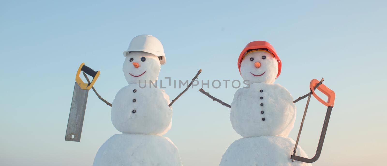 Snowman builder in winter in helmet. Christmas snow man, building and repair work