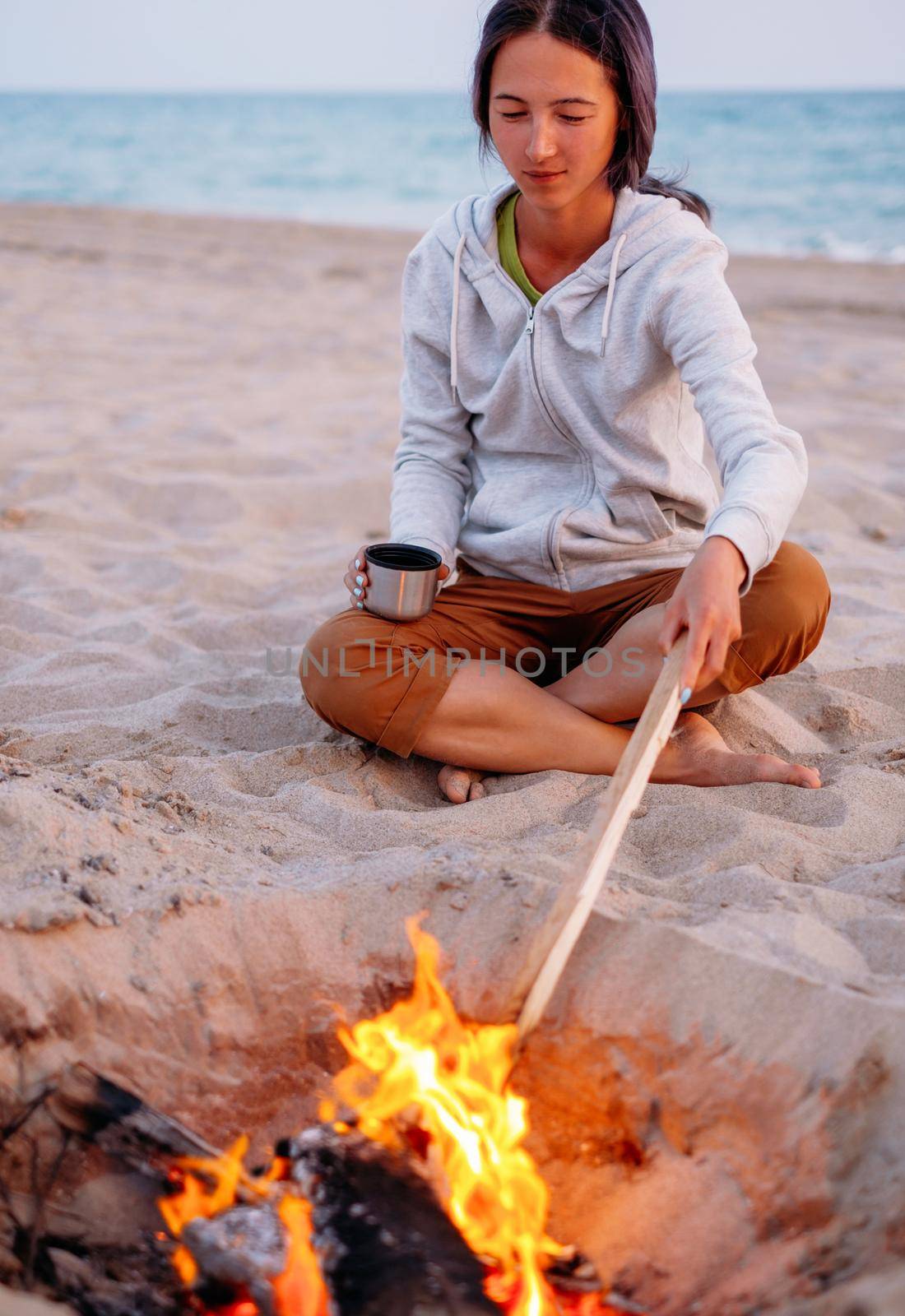 Woman relaxing near a campfire on beach. by alexAleksei