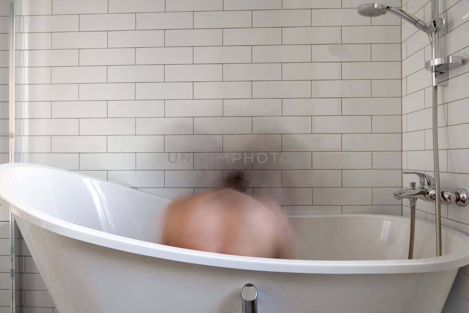 Unrecognizable person feels bad and shows mental problems while sitting in the bathroom. Blurred man lonely in white space