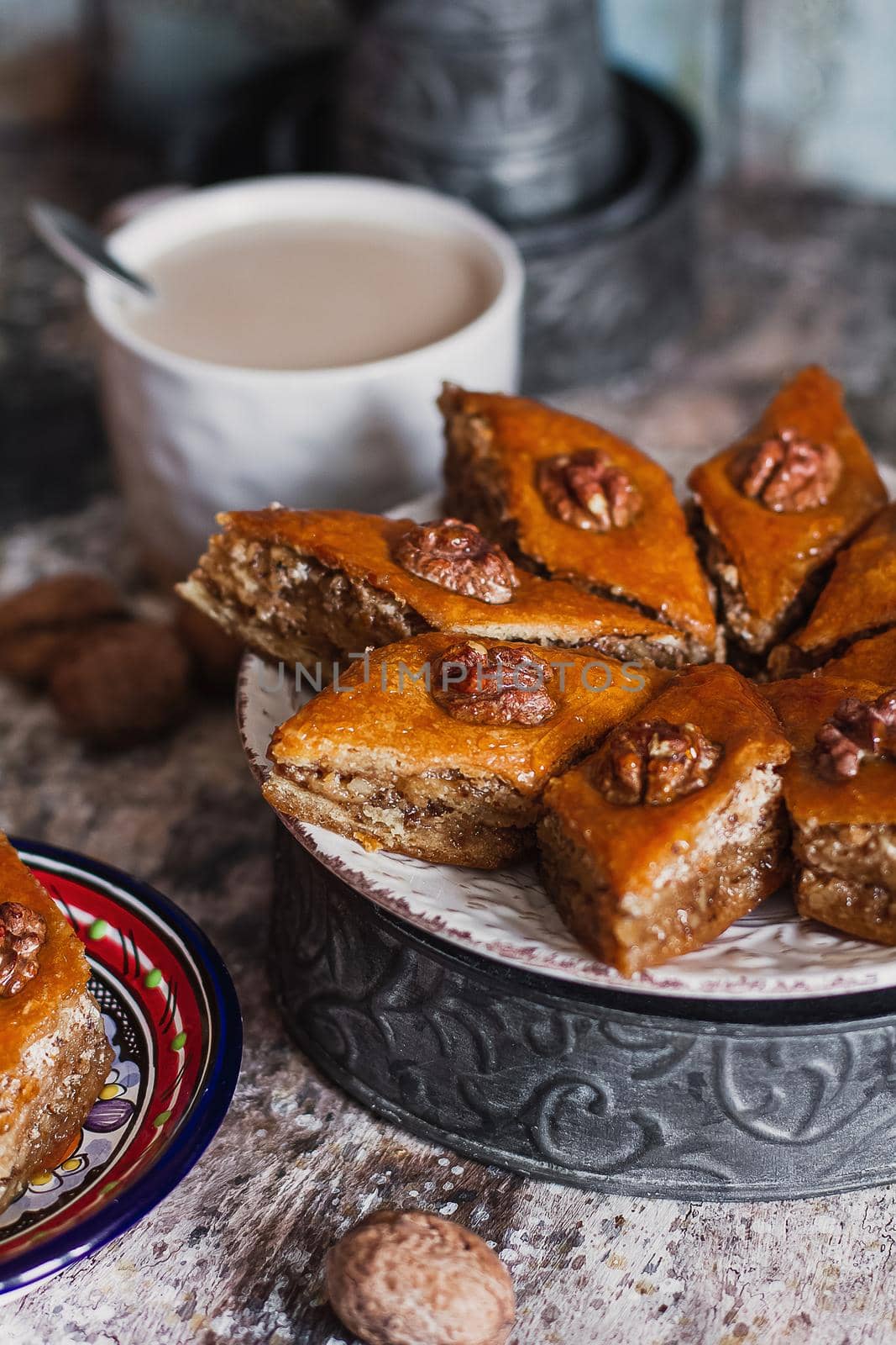 Assorted baklava. A Turkish ramadan arabic sweet dessert on a decorative plate, with coffee cup in the background. Middle eastern food baklava with nuts and honey syrup.