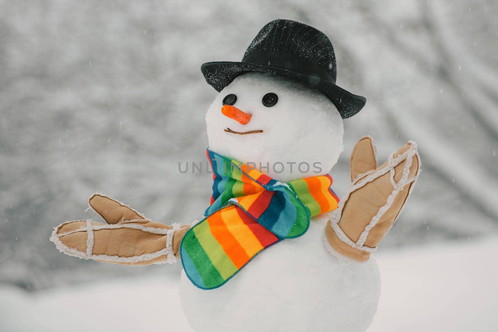 Snowman with hat and scarf in winter outdoor. Happy smiling snow man on sunny winter day. Christmas card