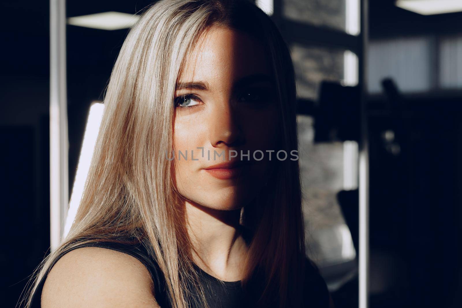 Close up portrait of a beautiful blonde woman with long hair smiling in dark room