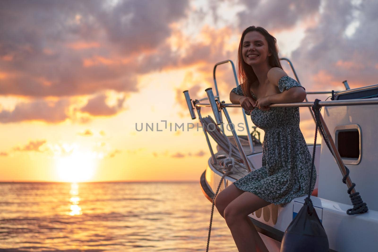 Young attractive woman sitting on the deck of yacht and enjoying sunset by Fabrikasimf