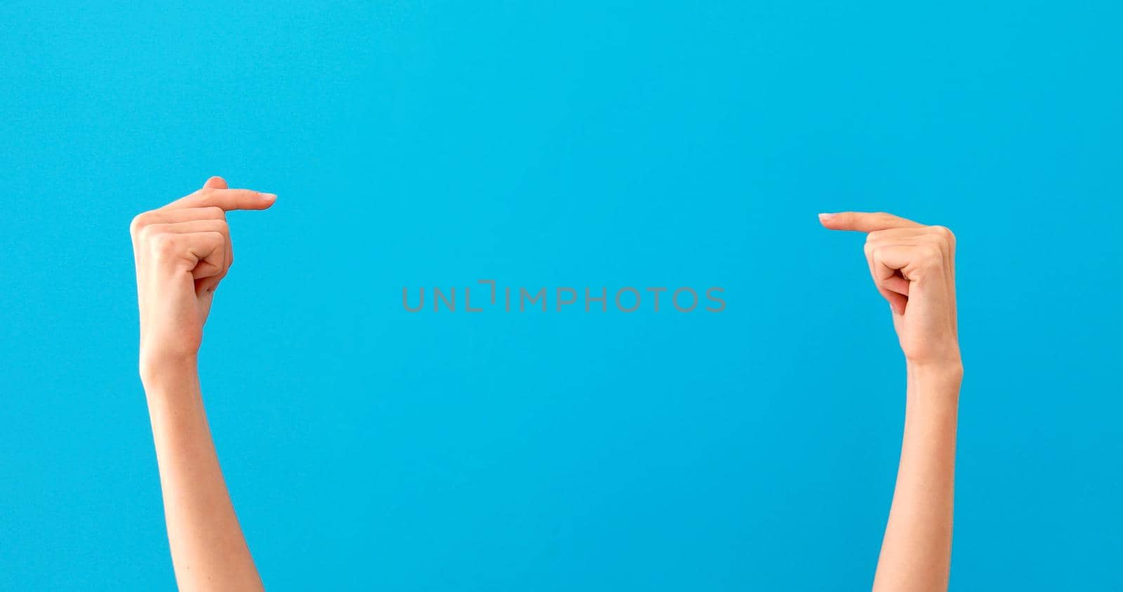 Woman hands pointing on copyspace isolated over pastel blue background in studio. Copy space for advertisement. With place for text or image, promotional content. Advertising area, workspace mock up