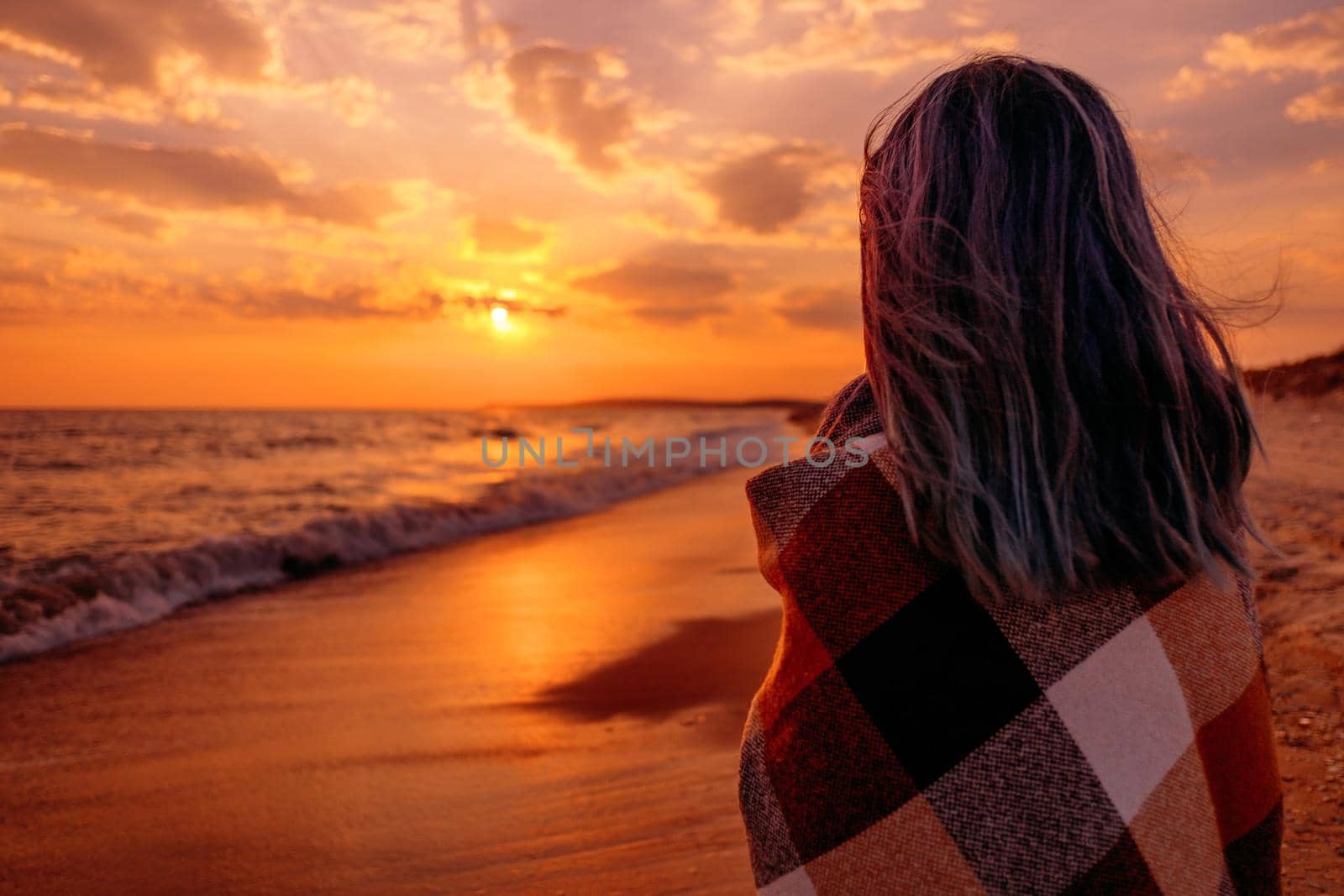 Young woman relaxing on coast near the sea at sunset in summer.