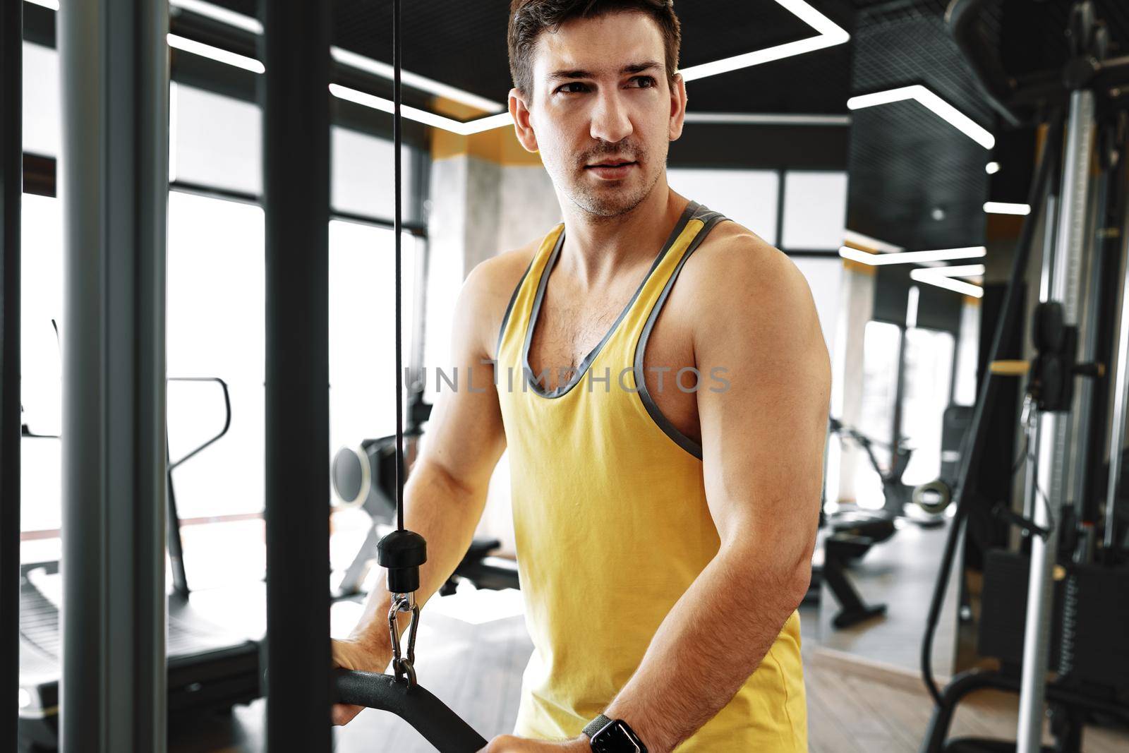 Young bodybuilder doing heavy weight exercise for biceps in a gym by Fabrikasimf