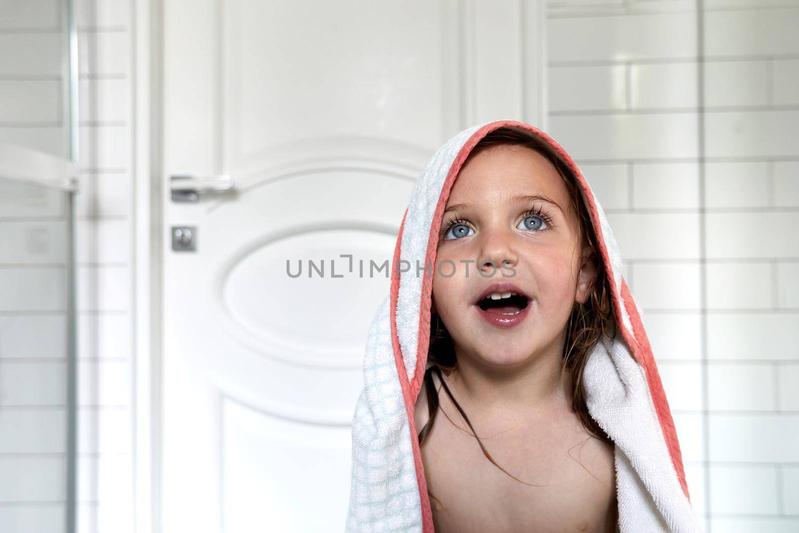 Charming nude girl with blue eyes and mouth opened in towel after washing routine in bathroom