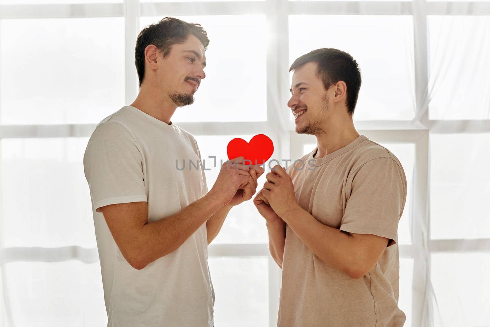 Gay couple celebrating valentine's day. A guy gives a valentine to man at home