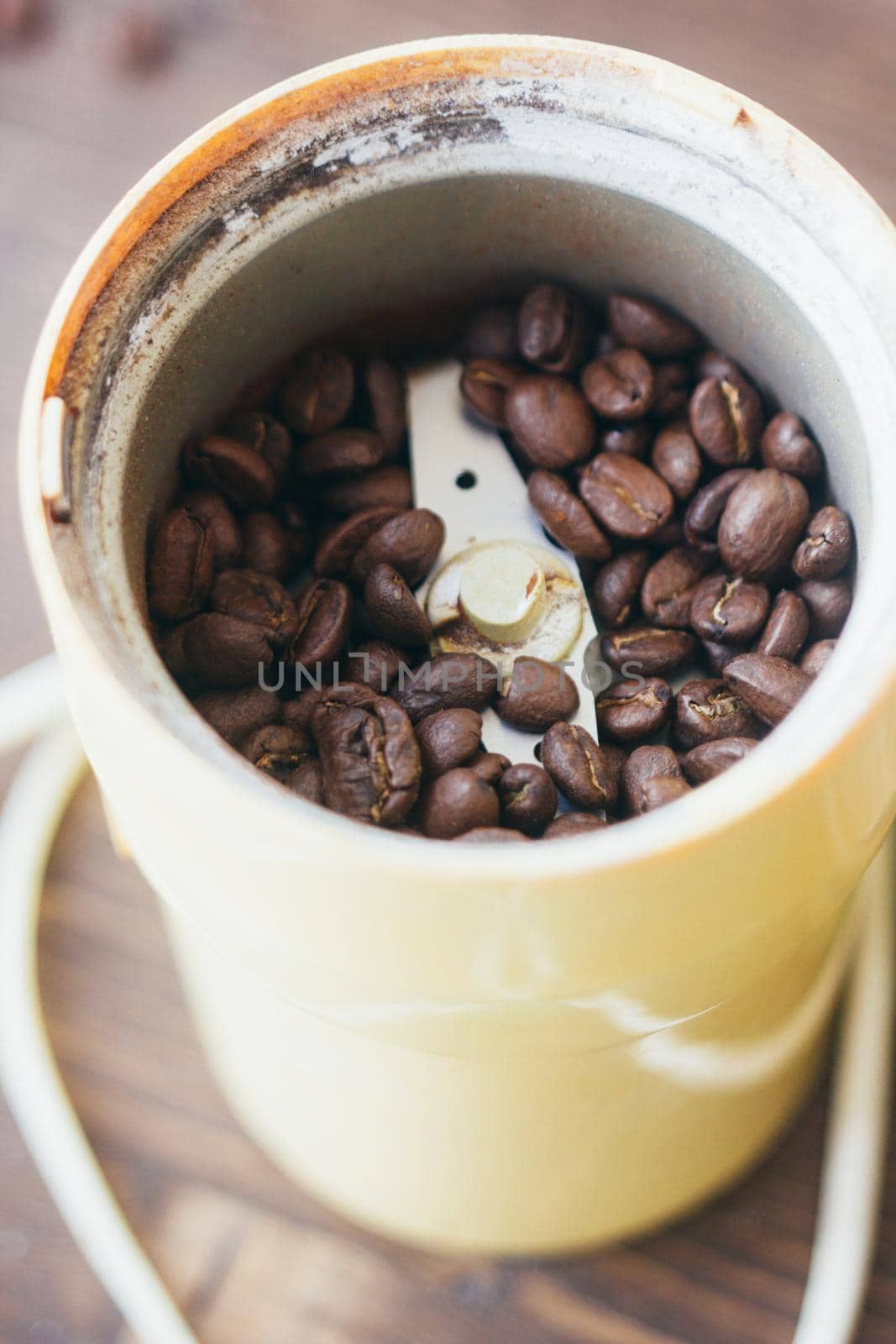 Electric coffee mill machine with coffee beans inside. Coffee grinder over the kitchen table