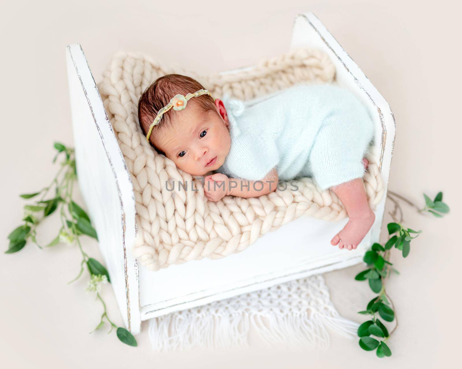 Lovely newborn lying awake on tiny bed