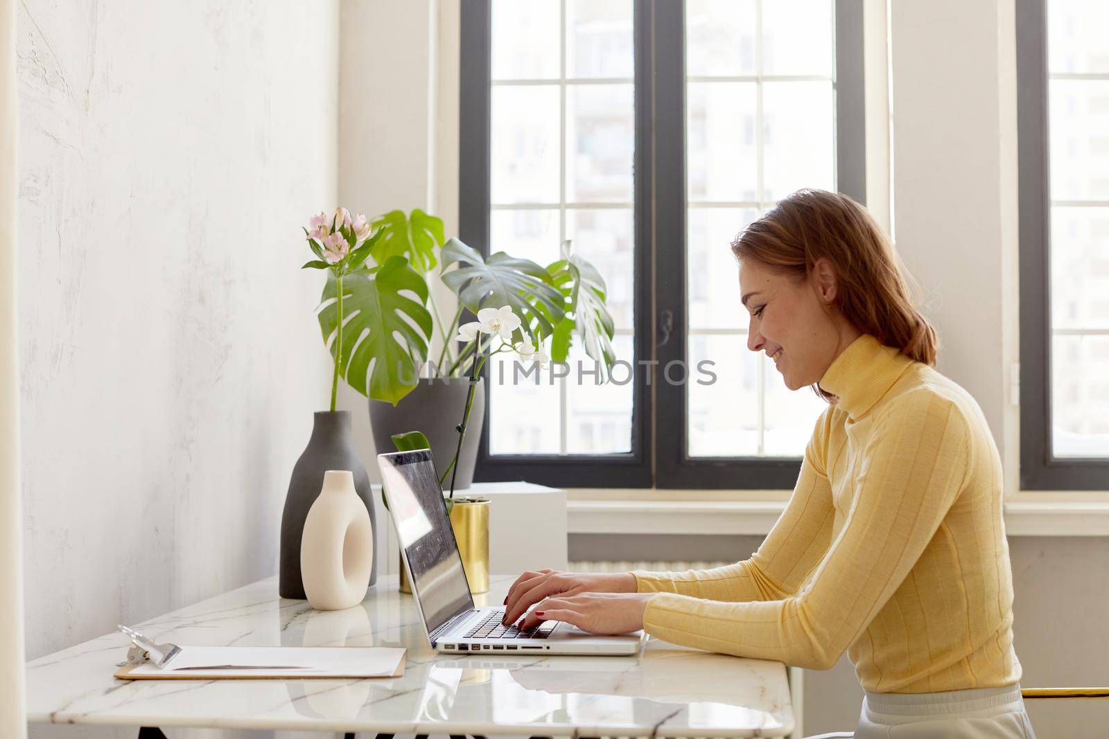 Smiling girl sitting at the table and working on laptop by Demkat