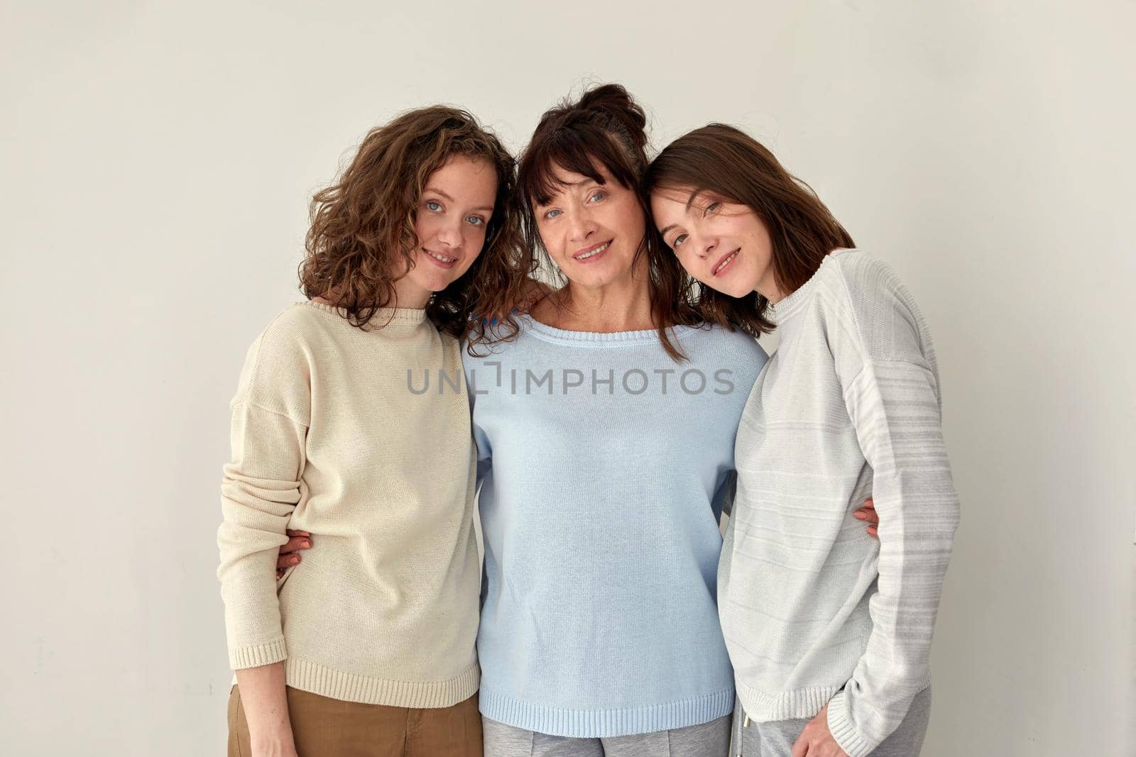 Smiling mother hugging daughters and looking at camera by Demkat