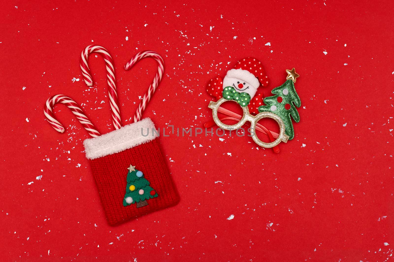 Christmas red sack with candy and Christmas glasses at red background with snow by uveita