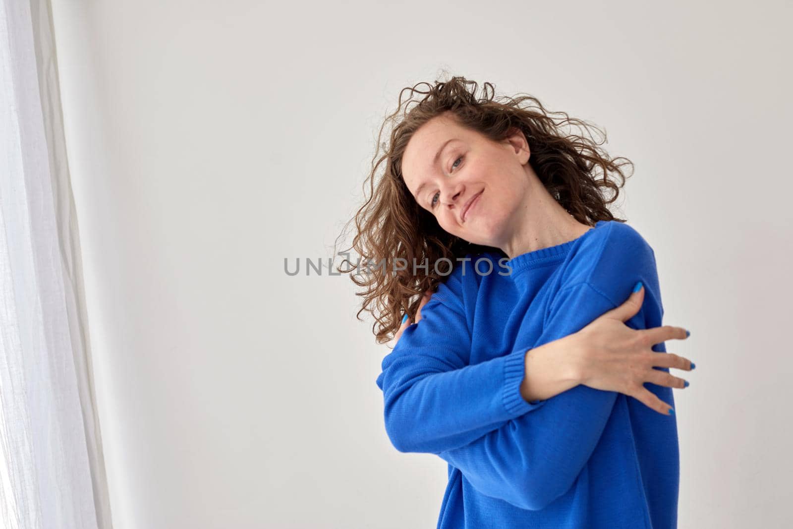 Self hug of happy confident young woman against white wall background by Demkat