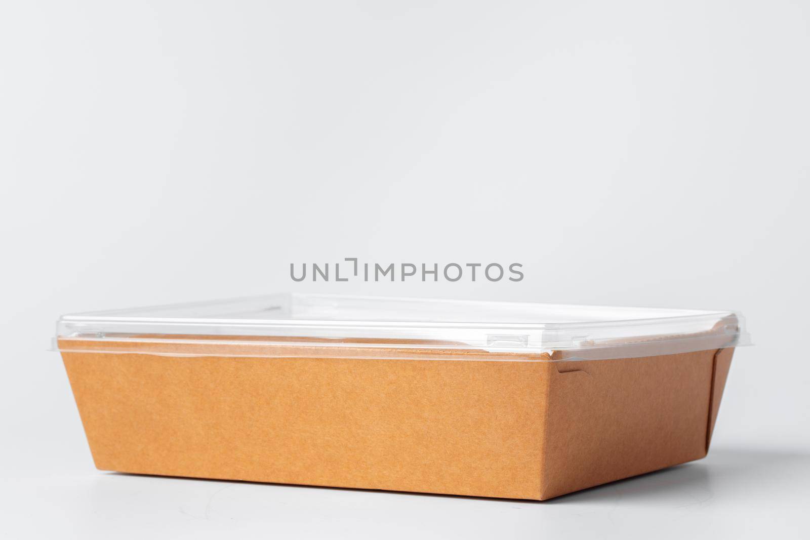 Craft paper disposable box with plastic cover on grey background, copy space, close up