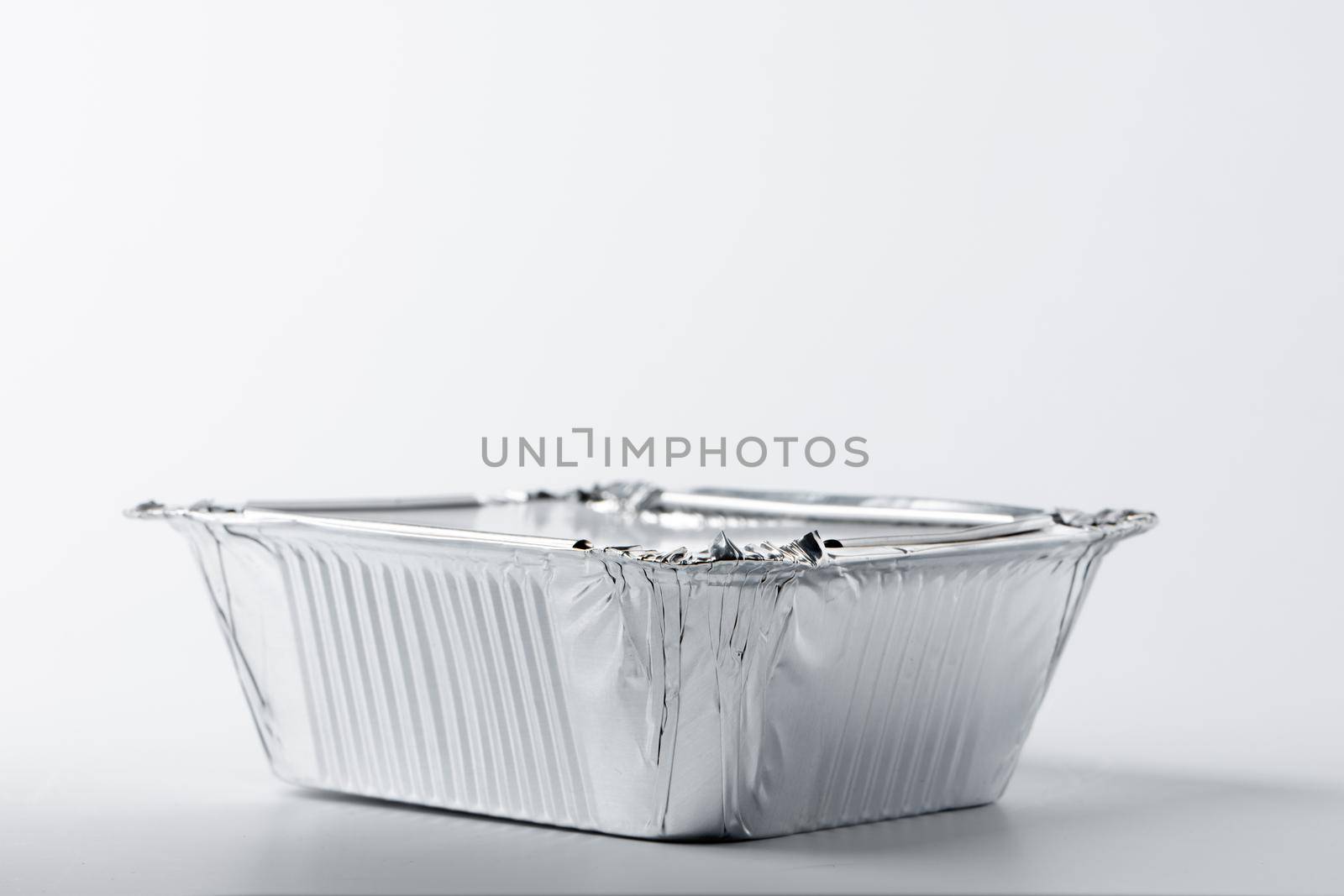 Foil food box with takeaway meal on white background close up