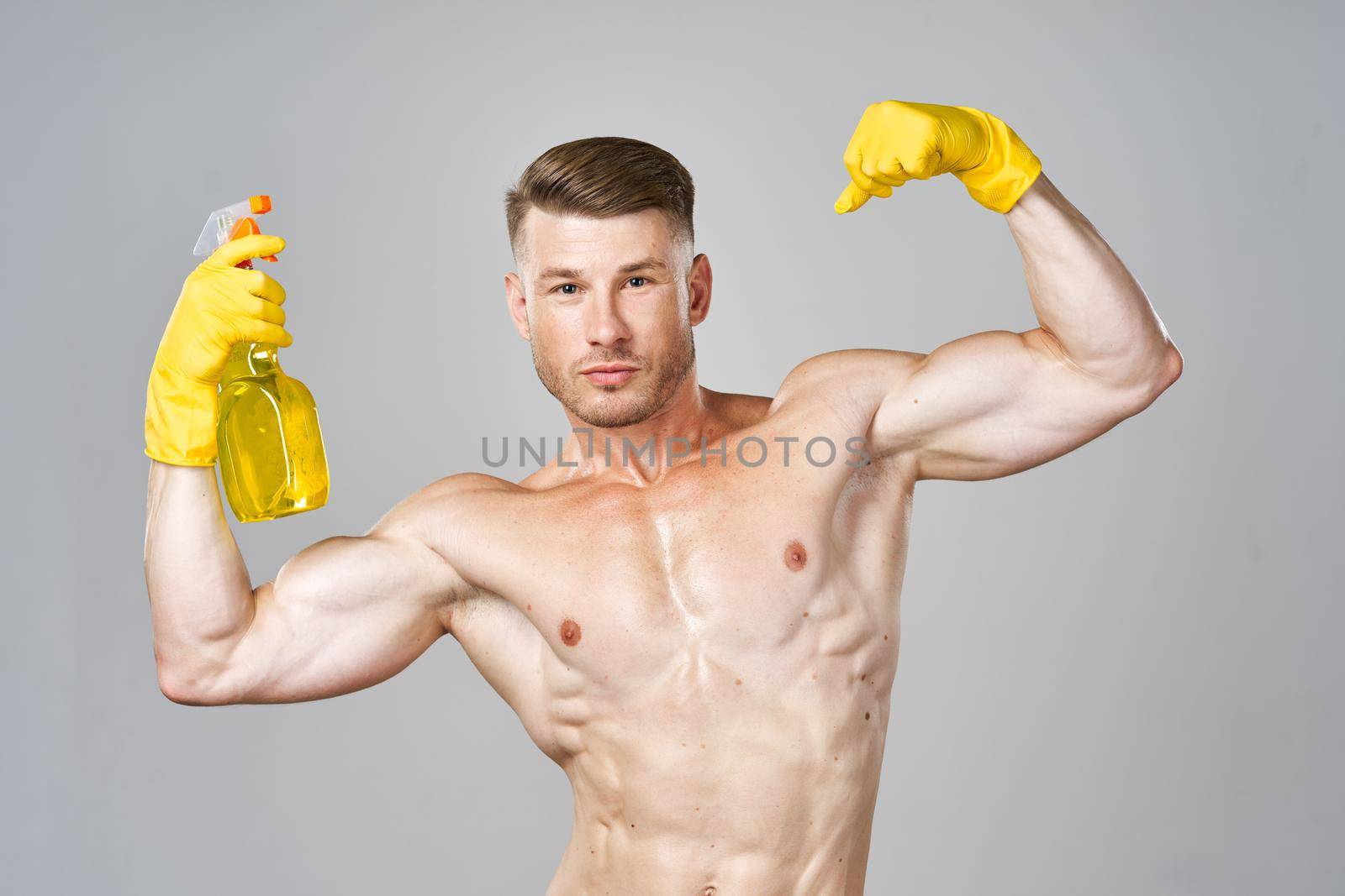 man in yellow rubber gloves with pumped muscles detergent cleaning. High quality photo