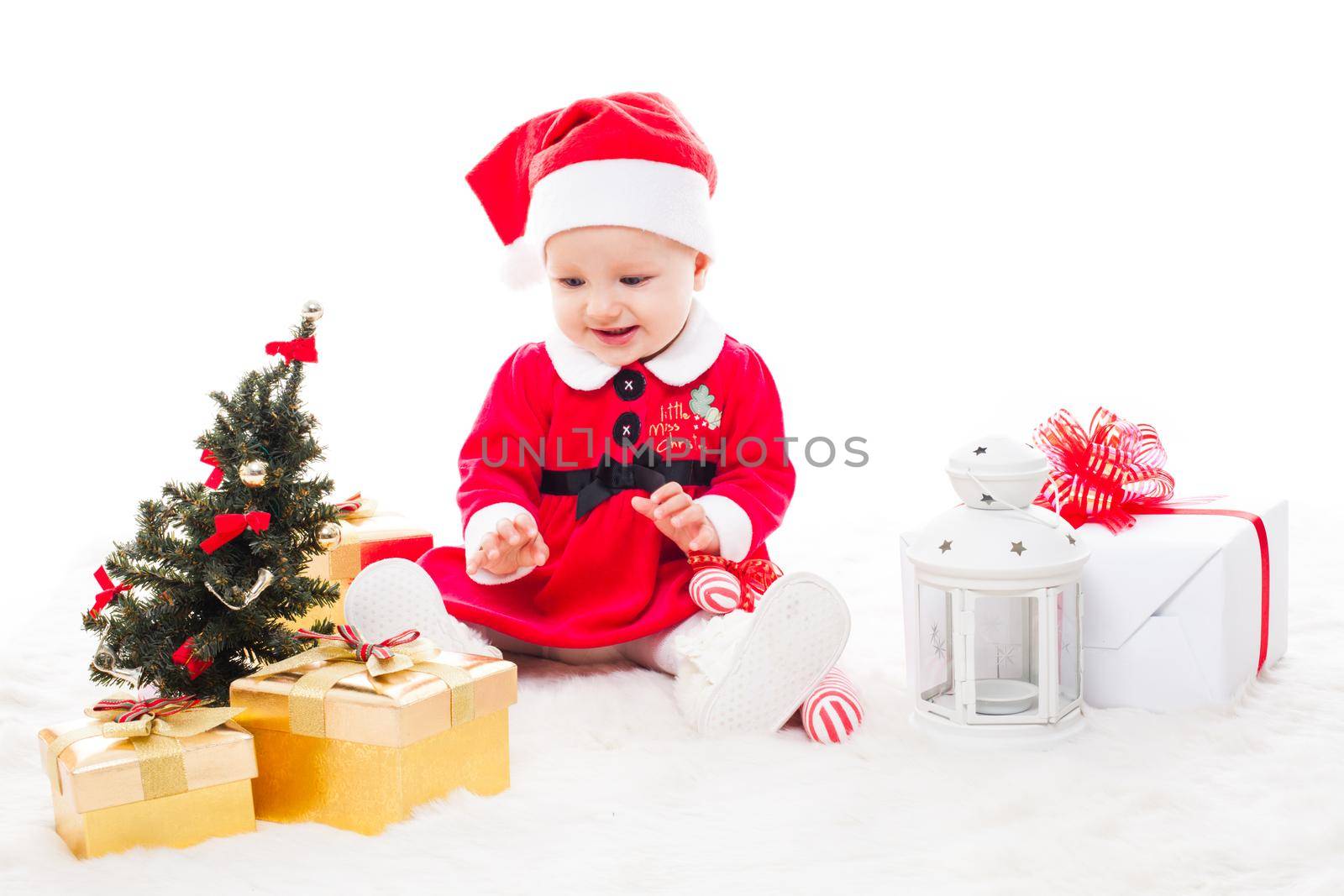 Santa baby girl with gift box and christmas decorations on a fur