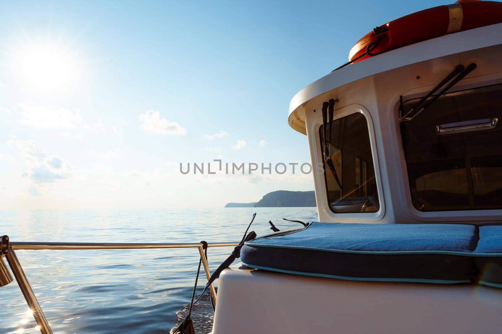 Deck of white yacht sailing in open sea at sunset, close up