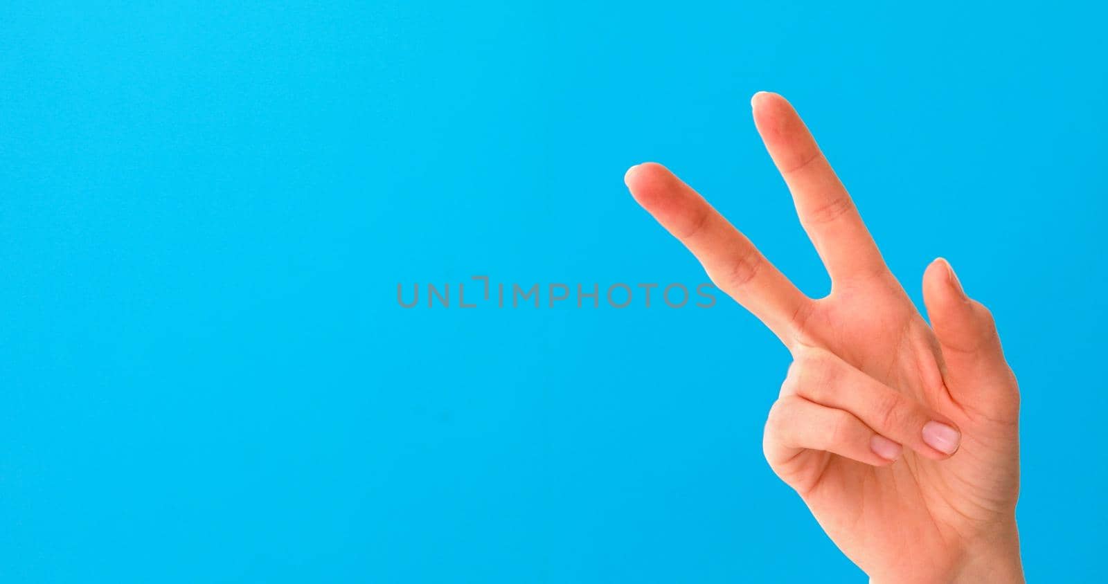 Woman hand doing victory sign isolated on blue by Demkat