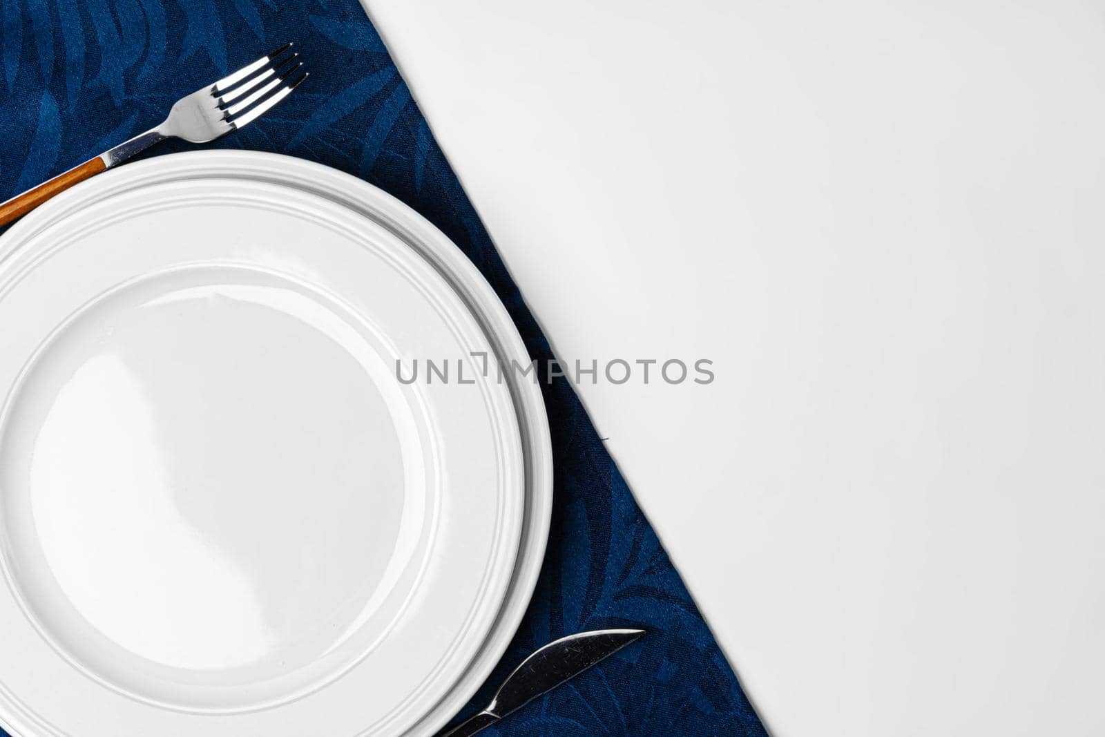 Fork, knife and plate on towel. Isolated on white background. by Fabrikasimf