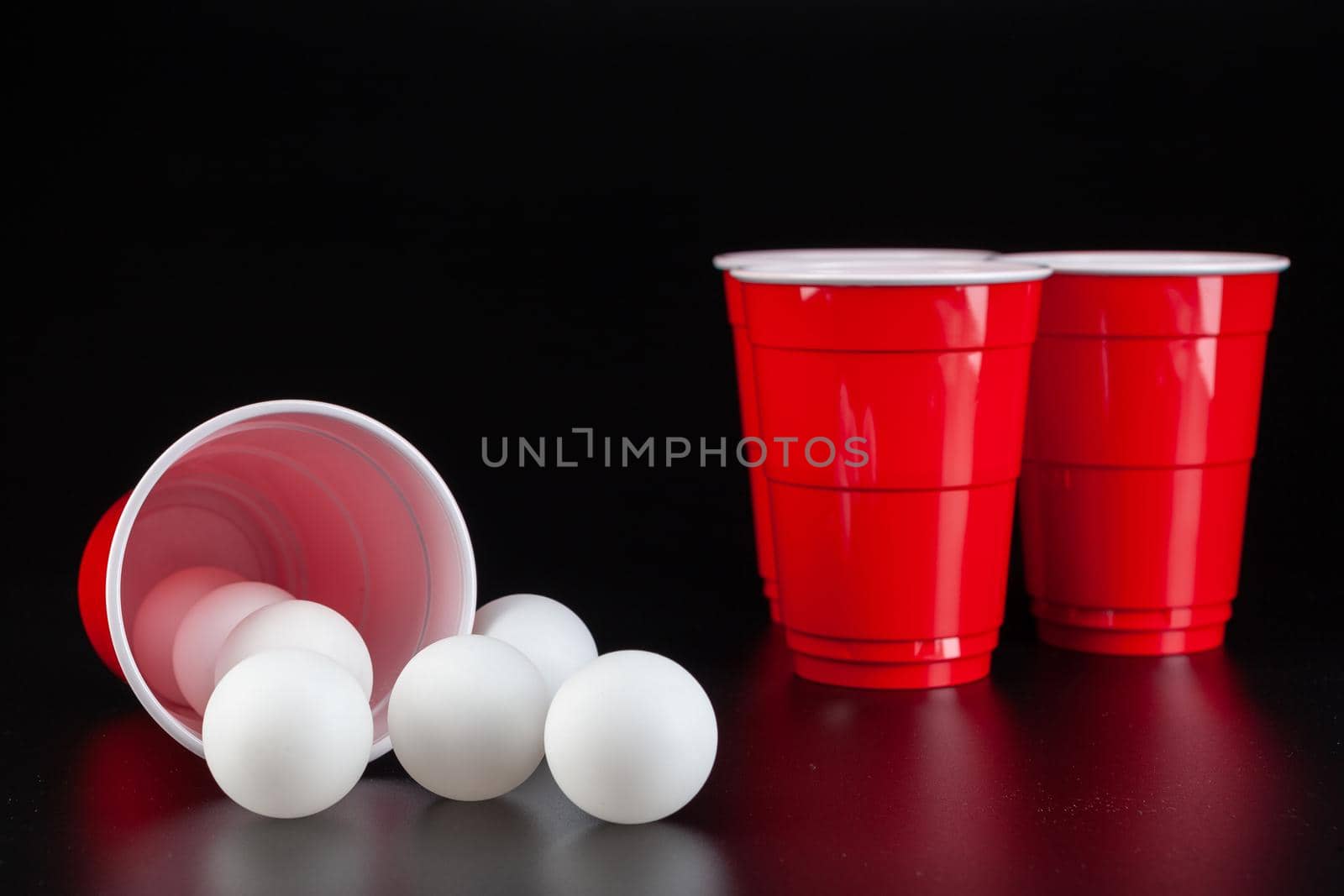 Red plastic cups and ball for game of beer pong. Close up.