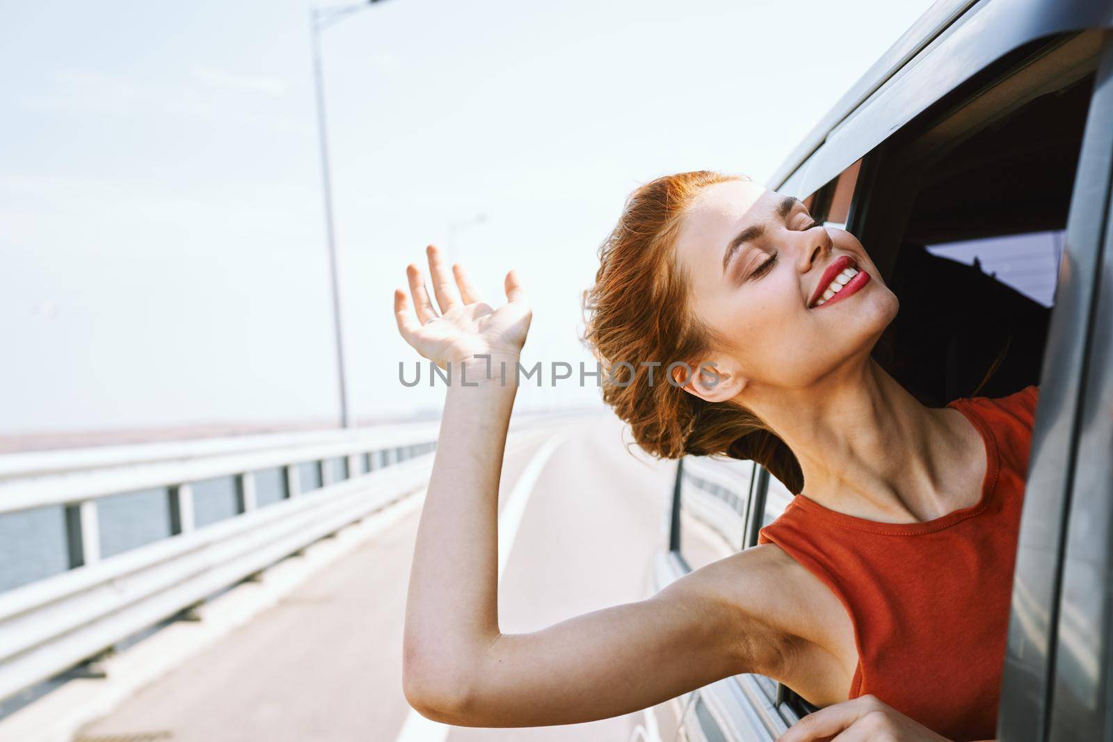 cheerful woman peeking out of the car window trip road travel by Vichizh
