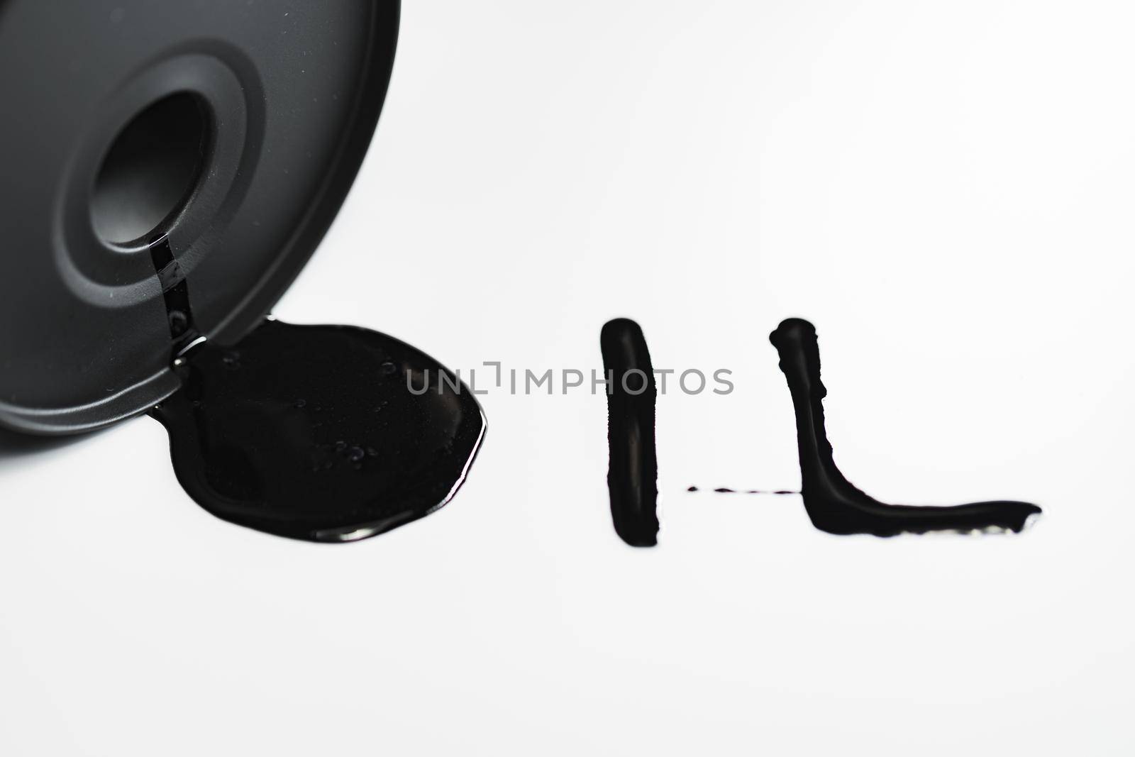 Oil industry concept. Spilled oil from a mini barrel isolated on a white background