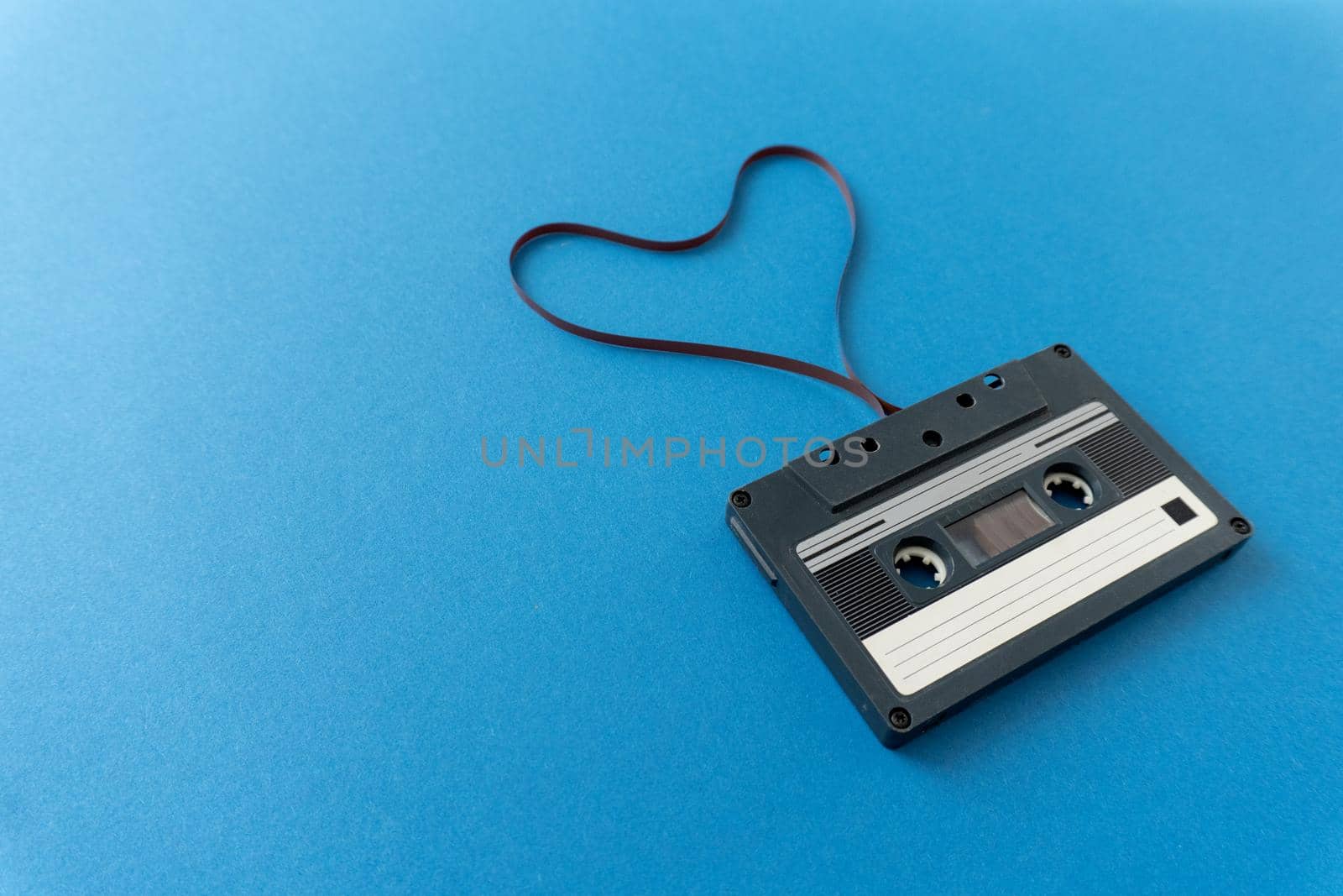 Retro audio cassete with magnetic tape in shape of heart. by uveita