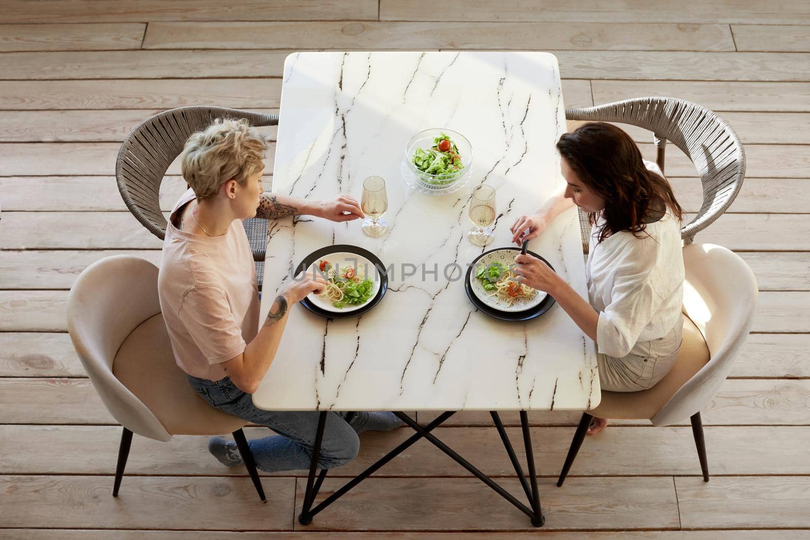 Couple enjoying dinner meal sitting at kitchen table together and drinking white wine, healthy eating view from above
