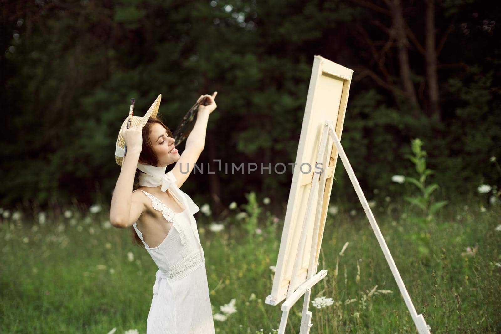 pretty woman artist paints a picture on nature landscape. High quality photo