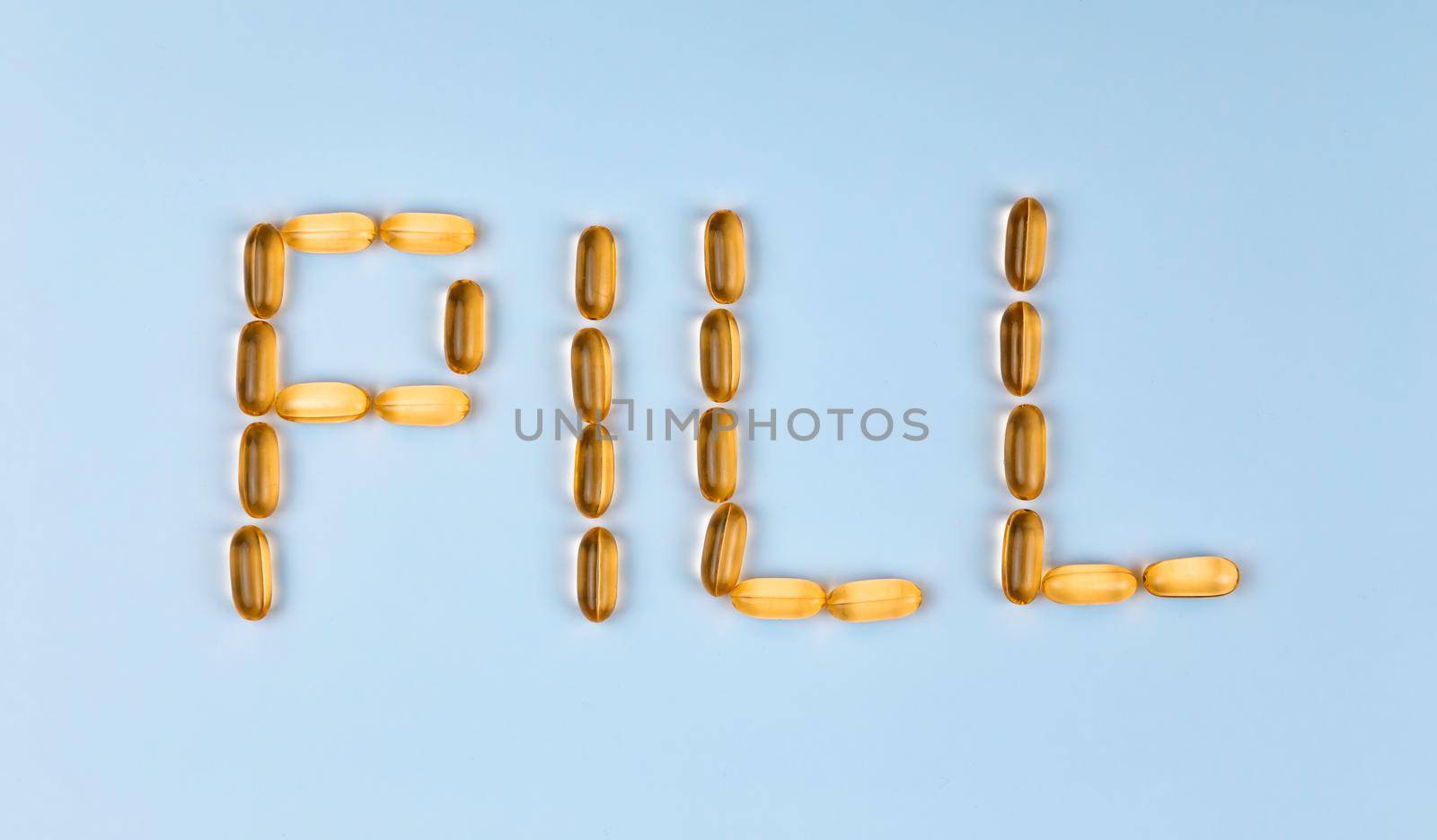 The word Pill is laid out with tablets. The word Pill is laid out with gel pills on a blue background with copy space for text